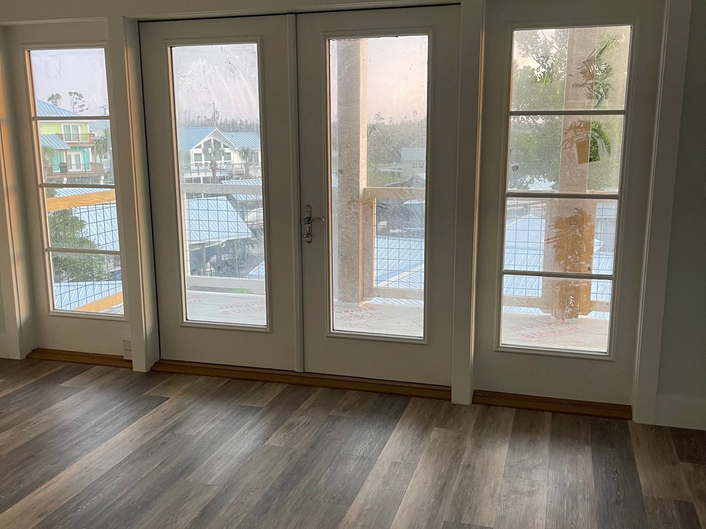 Finished coastal home interior with glass doors and wood flooring